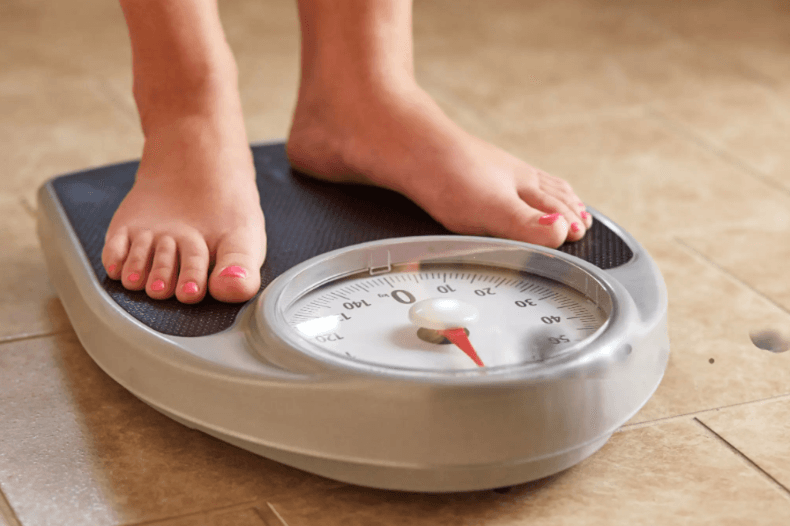 woman stepping on weighing scale